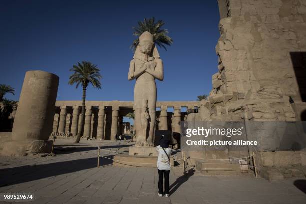 Picture issued on 24 December 2017, shows a tourist taking pictures of the of Rames II statue at the entrance of Karnak Temple, in Luxor, Upper...
