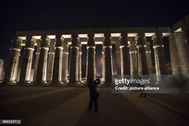 Picture issued on 24 December 2017, shows tourists taking photos of the illuminated columns of Amenhotep III during a light show at the Luxor Temple...