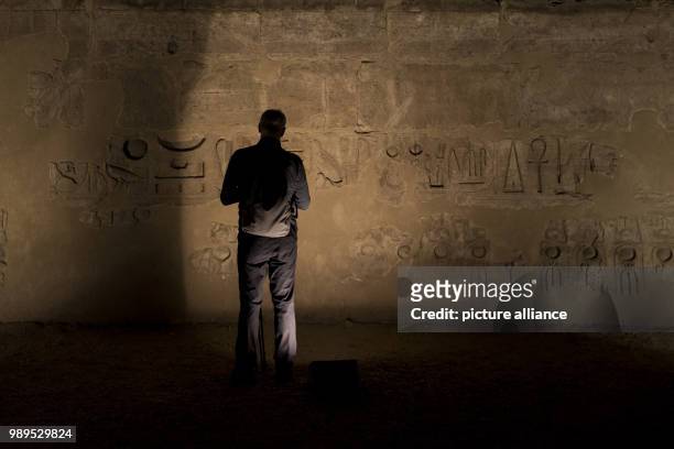 Picture issued on 24 December 2017, shows a tourist looking at an illuminated mural during a light show at the Luxor Temple in Luxor, Upper Egypt, 10...