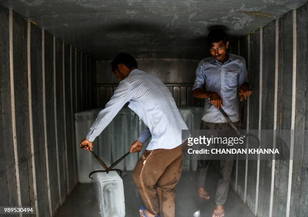 In this photograph taken on June 29 Indian labourers load ice blocks into a transportation van in an ice factory in Noida, some 20km east of New...