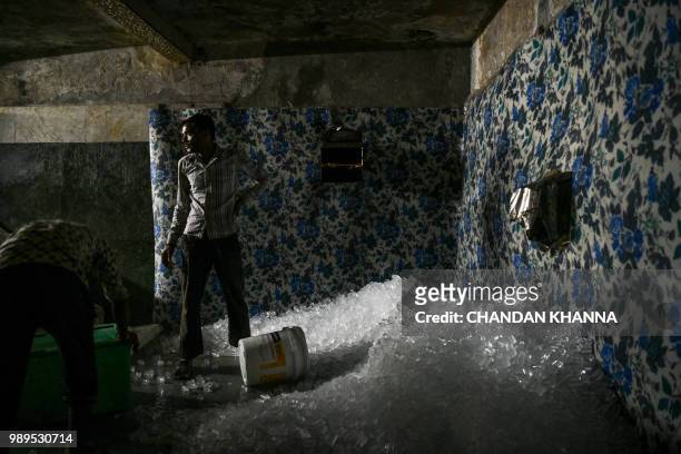 In this photograph taken on June 27 Indian labourers pack ice cubes for delivery in an ice factory in Noida, some 20km east of New Delhi. Keeping...