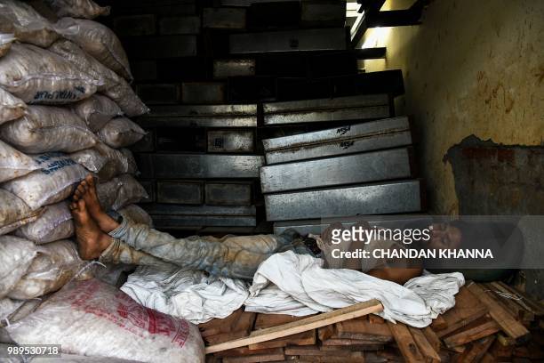 In this photograph taken on June 27 an Indian labourer sleeps in an ice factory in Noida, some 20km east of New Delhi. - Keeping people cool in...