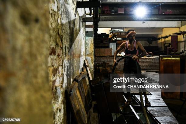 In this photograph taken on June 27, 2018 an Indian labourer puts water in ice blocks for freezing in an ice factory in Noida, some 20km east of New...