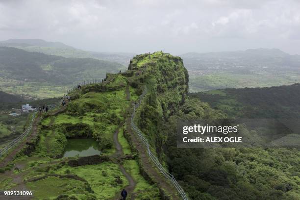 In this photo taken on June 30, 2018 visitors walk along the ruins of the Lohagad hill fort, near Lonavla in the western Indian state of Maharashtra....