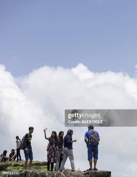 In this photo taken on June 30, 2018 visitors take a selfie at the ruins of the Lohagad hill fort, near Lonavla in the western Indian state of...