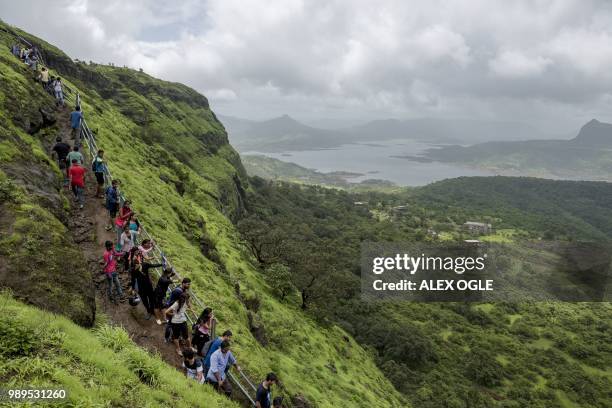 In this photo taken on June 30, 2018 visitors walk along the ruins of the Lohagad hill fort, near Lonavla in the western Indian state of Maharashtra....