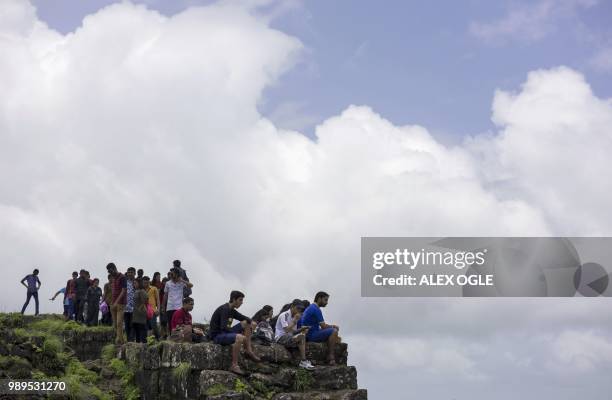 In this photo taken on June 30, 2018 visitors rest at the top of the ruins of Lohagad hill fort near Lonavla in the western Indian state of...