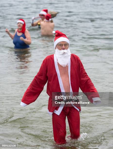 Man dressed as Santa takes part in the "Berliner Seehunde" club's Christmas swim at Orankesee lake, Germany, 25 December 2017. Photo: Paul Zinken/dpa