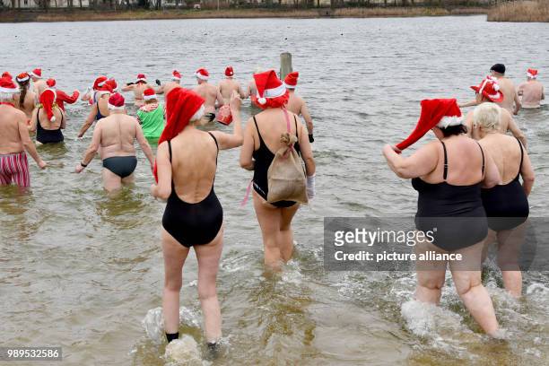 People taking part in the "Berliner Seehunde" club's Christmas swim at Orankesee lake in Berlin, Germany, 25 December 2017. Photo: Paul Zinken/dpa