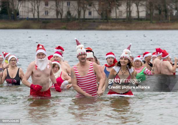 People taking part in the "Berliner Seehunde" club's Christmas swim at Orankesee lake in Berlin, Germany, 25 December 2017. Photo: Paul Zinken/dpa