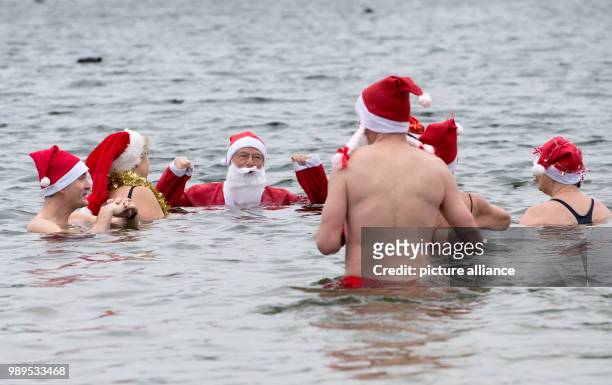 People take part in the "Berliner Seehunde" club's Christmas swim at the Orankesee lake in Berlin, Germany, 25 December 2017. Photo: Paul Zinken/dpa