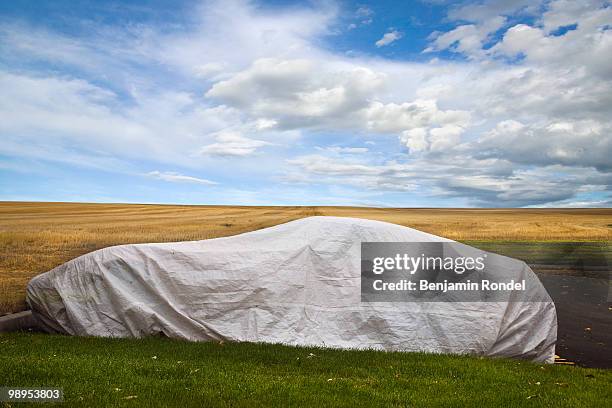 covered car for protection against the elements - tarpaulin stock-fotos und bilder