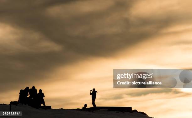 Man takes a picture of a group on hill during sunset near Horben, Germany, 25 December 2017. Photo: Patrick Seeger/dpa