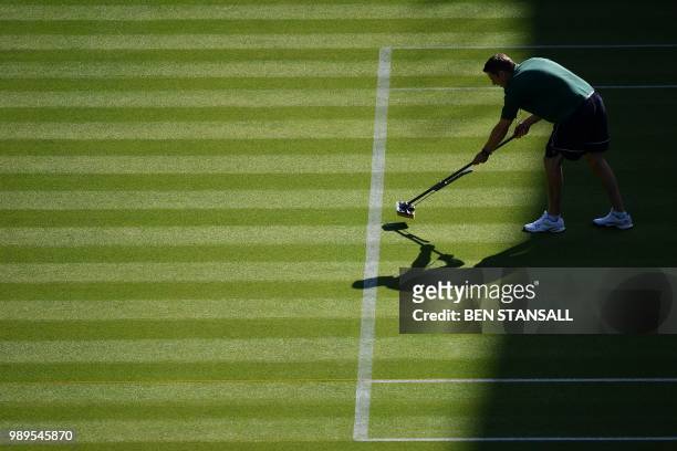 Groundsman mops the court on Centre Court at The All England Tennis Club in Wimbledon, southwest London, on July 2 on the first day of the 2018...