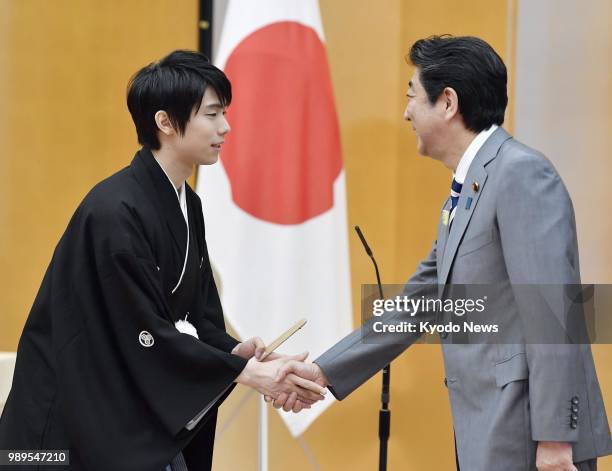 Two-time figure skating Olympic gold medalist Yuzuru Hanyu shakes hands with Japanese Prime Minister Shinzo Abe after receiving the People's Honor...