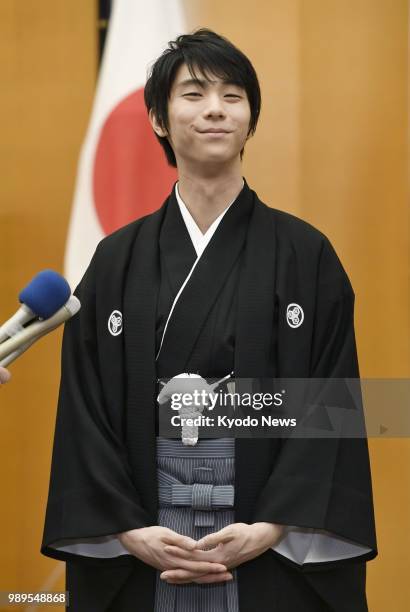 Two-time figure skating Olympic gold medalist Yuzuru Hanyu smiles as he answers questions from the press after receiving the People's Honor Award at...