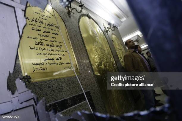 People reflected on the mirror of a damaged door inside the Mar Mina church, after a gun attack on the church in Helwan, Southeastern Cairo, Egypt,...