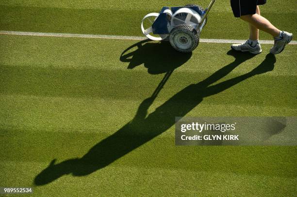 Groundsworkers tend to the grass courts at The All England Tennis Club in Wimbledon, southwest London, on July 2 on the first day of the 2018...