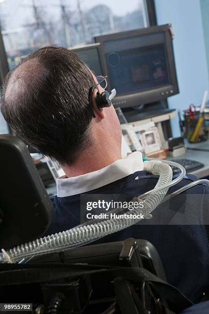 businessman with duchenne muscular dystrophy using a breathing ventilator in an office - ventilator stock pictures, royalty-free photos & images