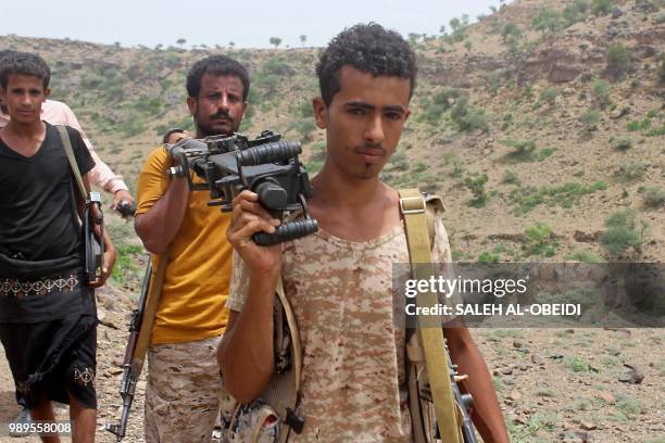 Yemeni pro-government fighters carry a heavy machine gun as Emirati supported forces take over Huthi bases on the frontline of Kirsh between the...