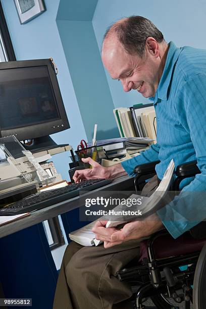 businessman with friedreich's ataxia in a wheelchair referring to a directory in an office - referring photos et images de collection