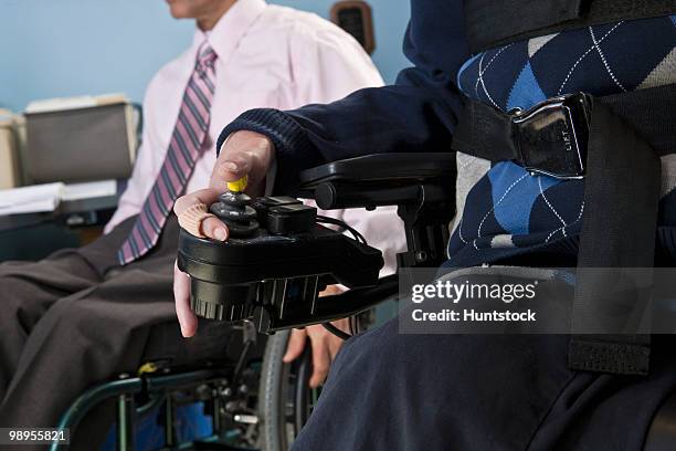 businessman with duchenne muscular dystrophy using a motorized wheelchair beside his colleague with spinal cord injury - spinal cord injury stock-fotos und bilder