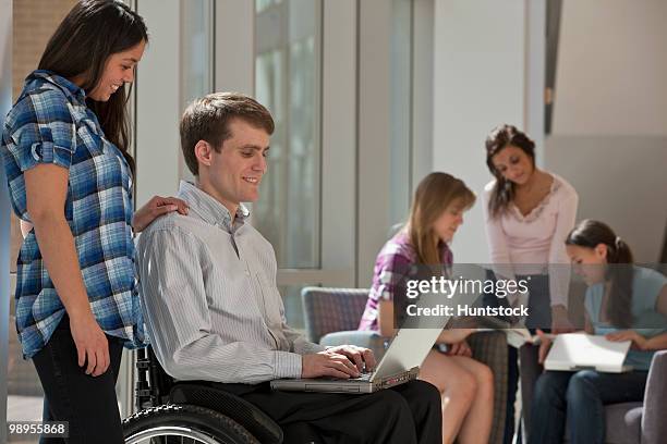 teacher with spinal cord injury using a laptop with students - spinal cord injury stock-fotos und bilder