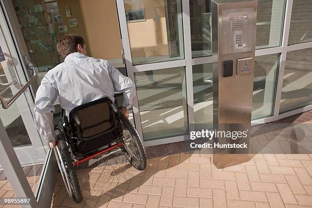 businessman with spinal cord injury in a wheelchair entering to office building - spinal cord injury stock-fotos und bilder