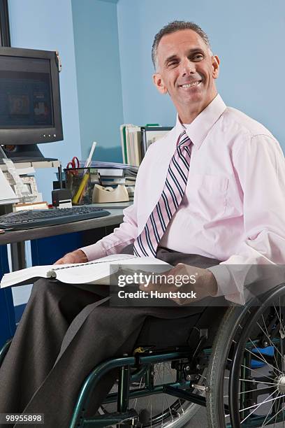 businessman with spinal cord injury in a wheelchair with a book in an office - spinal cord injury stock-fotos und bilder