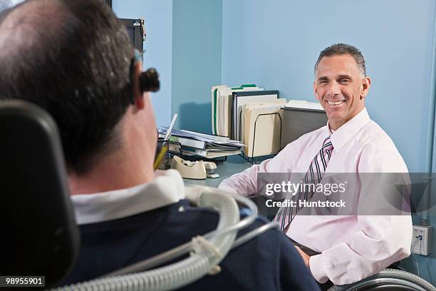 businessman with spinal cord injury talking to his colleague on a ventilator and with duchenne muscular dystrophy - spinal cord injury stock-fotos und bilder