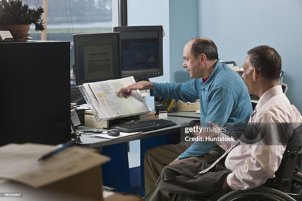 Two businessmen in an office, one with Friedreich's Ataxia and another with spinal cord injury