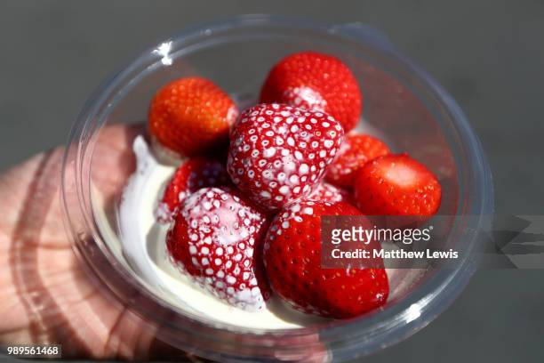 Spectator holds strawberries and cream on day one of the Wimbledon Lawn Tennis Championships at All England Lawn Tennis and Croquet Club on July 2,...