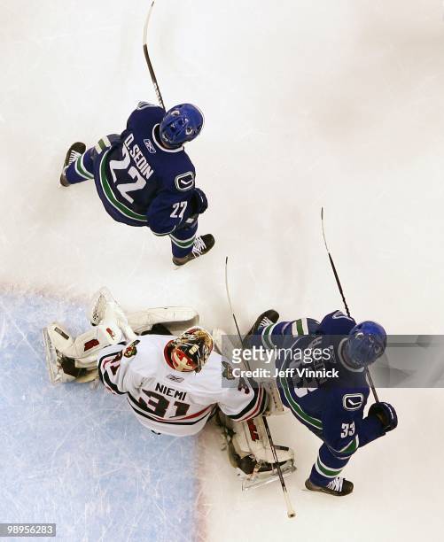 Daniel Sedin and Henrik Sedin of the Vancouver Canucks stand in front of Antti Niemi of the Chicago Blackhawks in Game Four of the Western Conference...