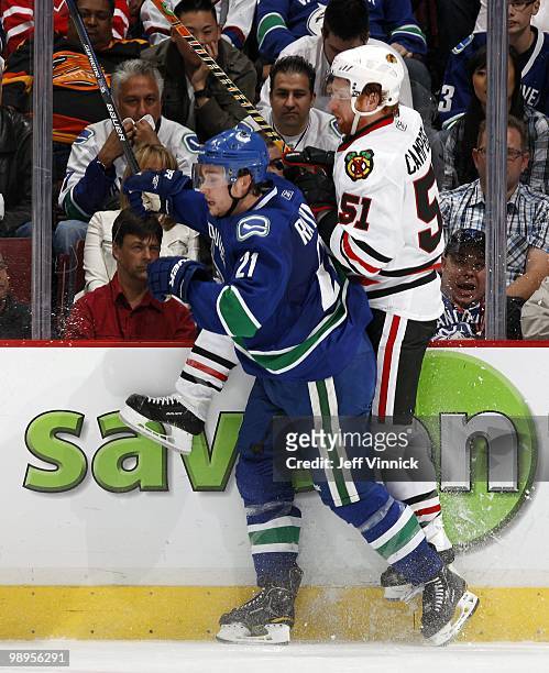 Mason Raymond of the Vancouver Canucks checks Brian Campbell of the Chicago Blackhawks into the boards during the national anthems in Game Four of...