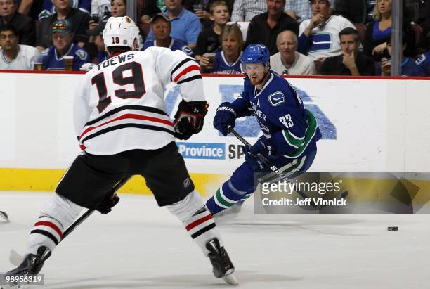 Jonathan Toews of the Chicago Blackhawks looks on as Henrik Sedin of the Vancouver Canucks skates up ice with the puck in Game Four of the Western...