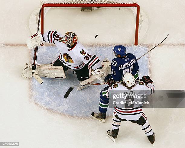 Duncan Keith of the Chicago Blackhawks and Mikael Samuelsson of the Vancouver Canucks watch a rebound behind Antti Niemi of the Chicago Blackhawks in...