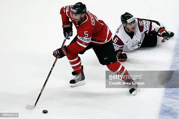 Marc Giordano of Canada eludes Kaspars Daugavins of Latvia on his way to score his team's fourth goal during the IIHF World Championship group B...