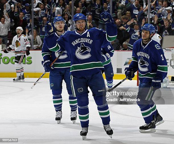 Patrick Sharp of the Chicago Blackhawks skates away dejected as Henrik Sedin of the Vancouver Canucks celebrates his goal with teammates Kevin Bieksa...