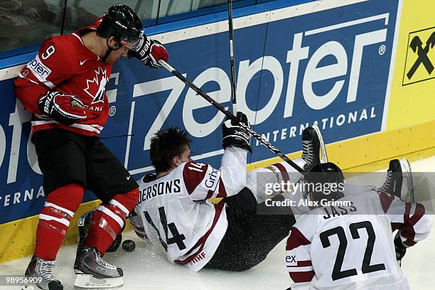 Janis Andersons of Latvia loses his helmet after being challenged by Steve Downie of Canada during the IIHF World Championship group B match between...