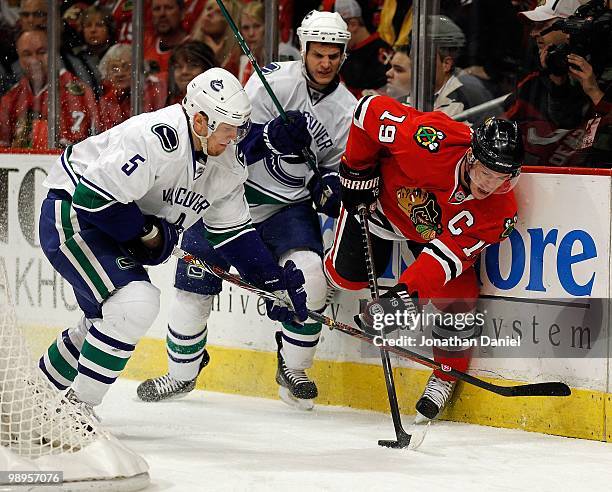 Jonathan Toews of the Chicago Blackhawks controls the puck under pressure from Christian Ehrhoff and Kevin Bieksa of the Vancouver Canucks in Game...