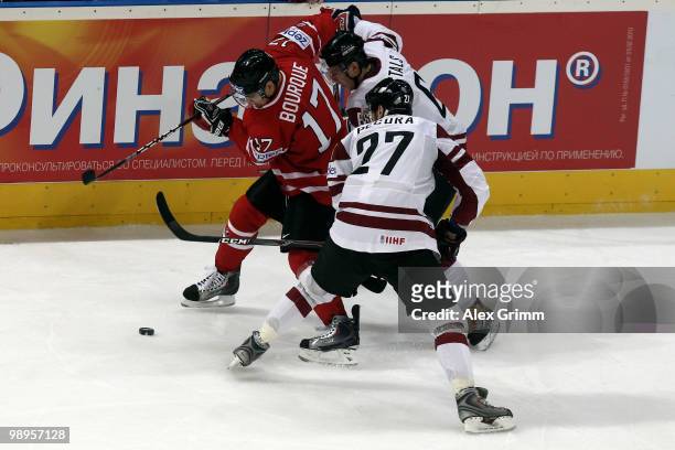 Rene Bourque of Canada is challenged by Janis Sprukts and Sergejs Pecura of Latvia during the IIHF World Championship group B match between...