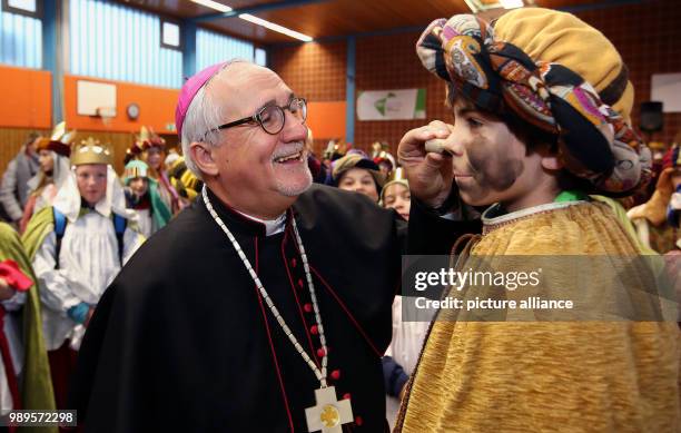 Dpatop - Gebhard Fuerst, Bishop of Rottenburg-Stuttgart , paints the face of a star singer black, referring to the Magi Melchior, during the opening...