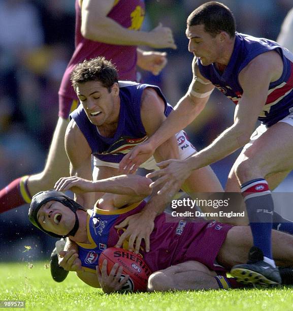 Shaun Hart of Brisbane is tackled by Craig Ellis and Simon Cox of the Bulldogs during the round 18 AFL match between the Brisbane Lions and the...