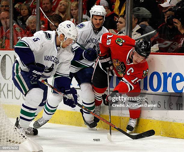 Jonathan Toews of the Chicago Blackhawks controls the puck under pressure from Christian Ehrhoff and Kevin Bieksa of the Vancouver Canucks in Game...