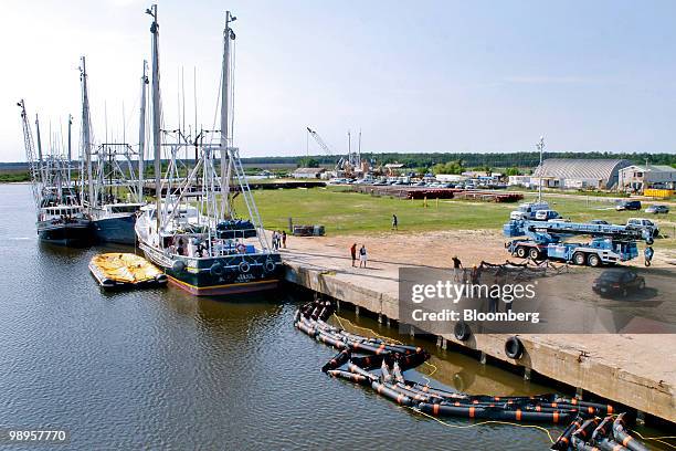 Oil containment booms used to skim oil off the water sit behind shrimping boats in Bayou La Batre, Alabama, U.S., on Sunday, May 9, 2010. Oil has...