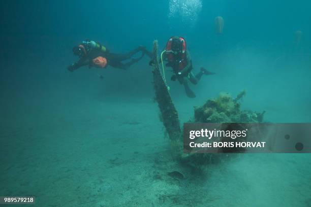 French military diver member of the FS Pluton M622 navy de-mining ship, swims on July 2 above the wreck of an USAAF P-47 Thunderbolt US fighter...