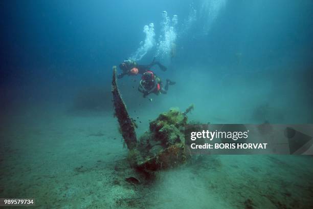 French military diver member of the FS Pluton M622 navy de-mining ship, swims on July 2 above the wreck of an USAAF P-47 Thunderbolt US fighter...