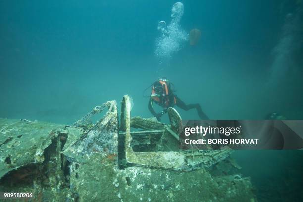 French military diver member of the FS Pluton M622 navy de-mining ship, swims on July 2 above the wreck of an USAAF P-47 Thunderbolt US fighter...