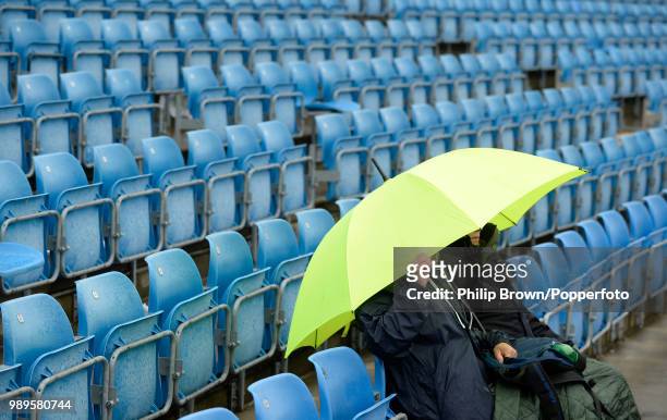 Spectators take shelter under an umbrella during a rain delay on day four of the 2nd Test match between England and New Zealand at Headingley, Leeds,...
