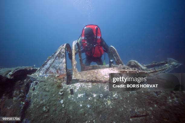 French military diver member of the FS Pluton M622 navy de-mining ship, swims on July 2 above the wreck of an USAAF P-47 Thunderbolt US fighter...